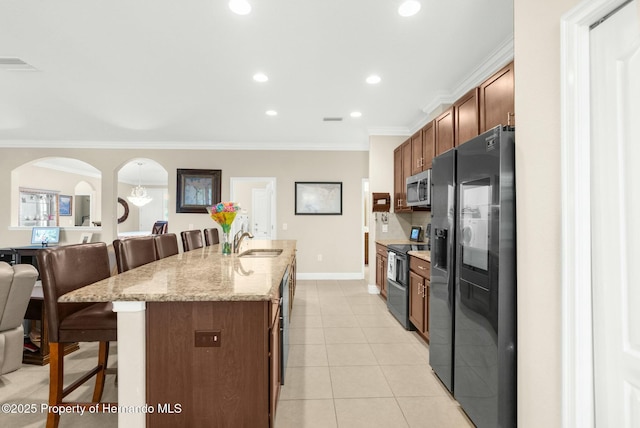 kitchen with a breakfast bar area, visible vents, black fridge, double oven range, and stainless steel microwave