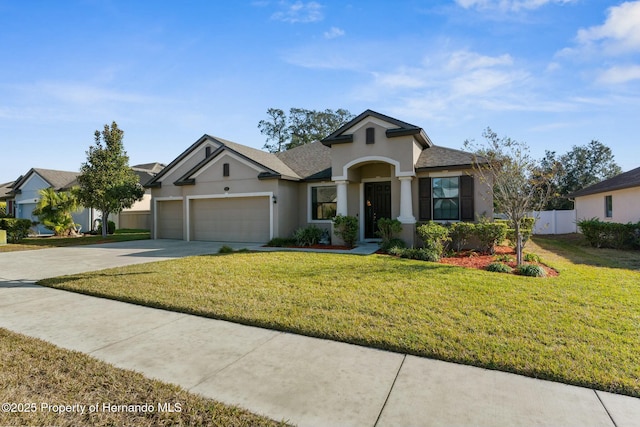 view of front of house featuring an attached garage, fence, concrete driveway, stucco siding, and a front yard