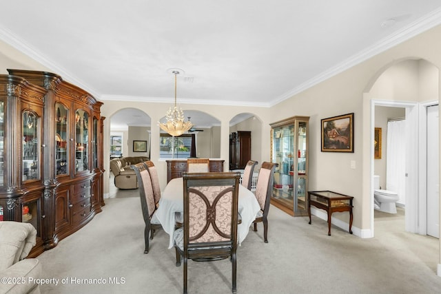 dining area with arched walkways, light colored carpet, crown molding, and baseboards