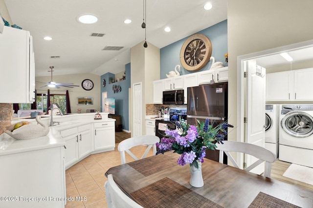 tiled dining space featuring ceiling fan, lofted ceiling, washer and clothes dryer, and sink