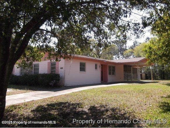 rear view of property with a carport and a yard