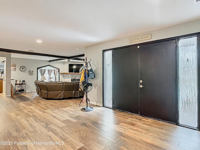 entryway with light hardwood / wood-style floors, ceiling fan, and a fireplace