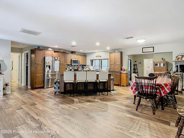 kitchen featuring a kitchen breakfast bar, a kitchen island, light wood-type flooring, and appliances with stainless steel finishes