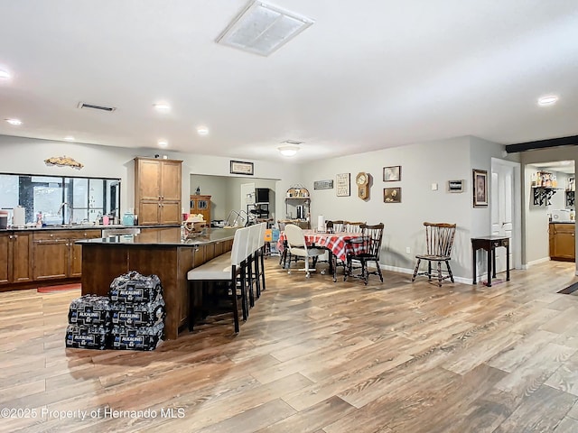 kitchen with sink, a center island, light hardwood / wood-style flooring, and a kitchen breakfast bar