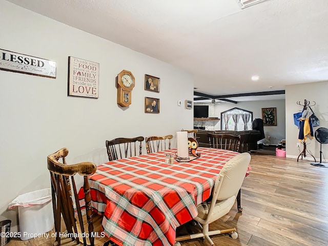 dining room with a fireplace, light wood-type flooring, and ceiling fan