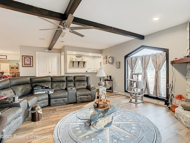 living room featuring ceiling fan, beamed ceiling, and light hardwood / wood-style floors