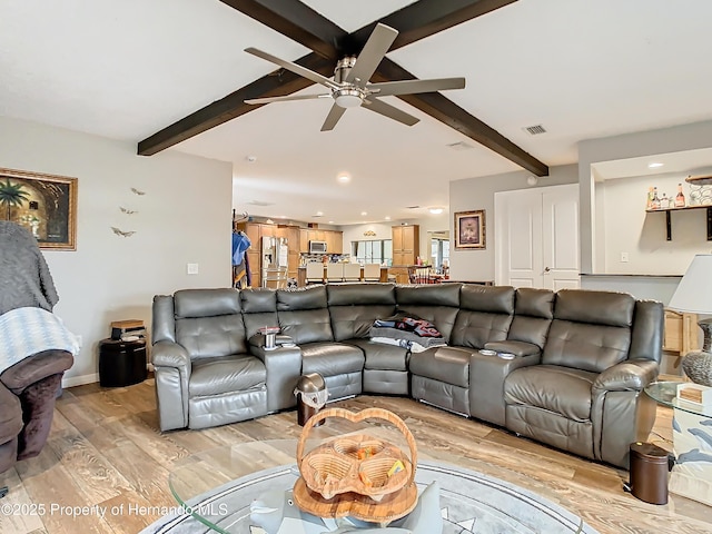 living room with ceiling fan, beamed ceiling, and light wood-type flooring