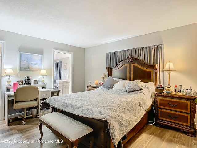 bedroom featuring connected bathroom and light hardwood / wood-style floors