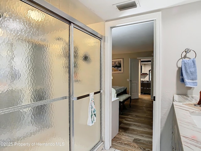 bathroom featuring vanity, a shower with shower door, and wood-type flooring