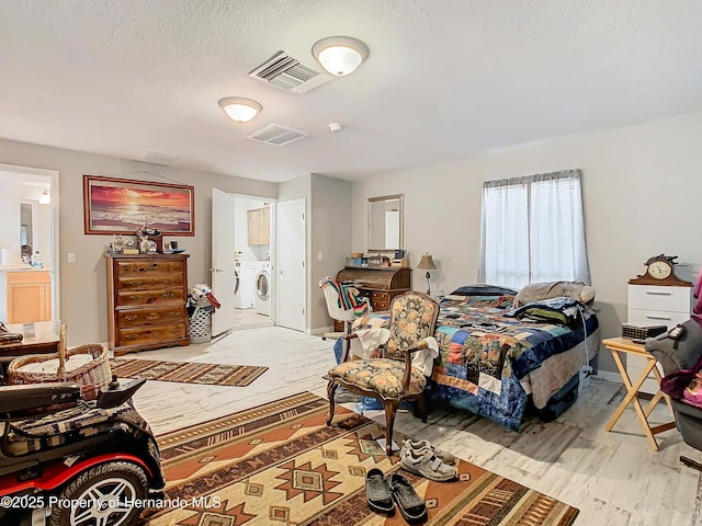 bedroom featuring a textured ceiling and washing machine and dryer