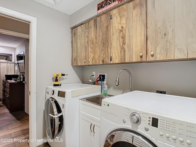 clothes washing area with sink, hardwood / wood-style flooring, cabinets, and washer and dryer