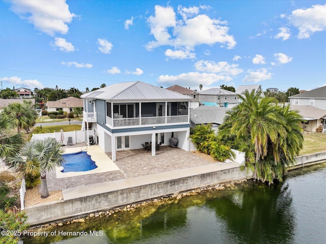 back of property featuring a fenced in pool, a sunroom, a water view, and a patio