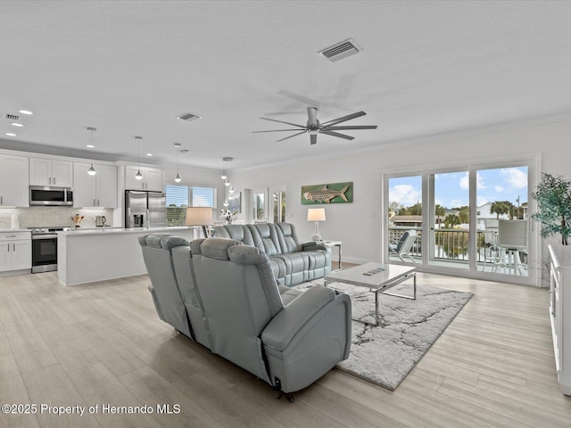 living room featuring ceiling fan, crown molding, and light hardwood / wood-style flooring