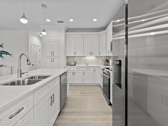 kitchen with sink, crown molding, hanging light fixtures, appliances with stainless steel finishes, and white cabinets