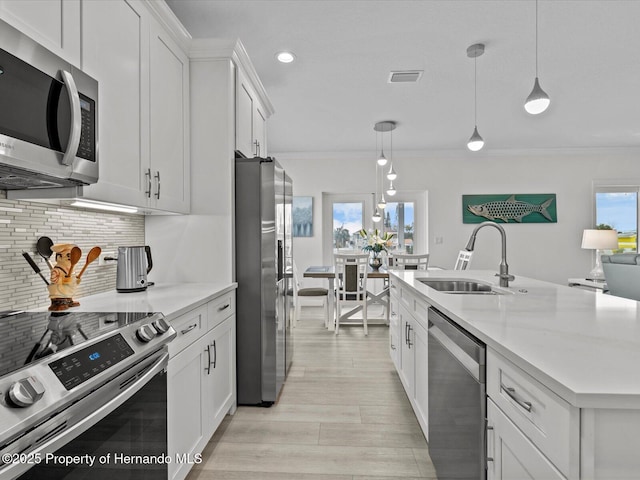 kitchen with appliances with stainless steel finishes, decorative light fixtures, crown molding, white cabinets, and sink