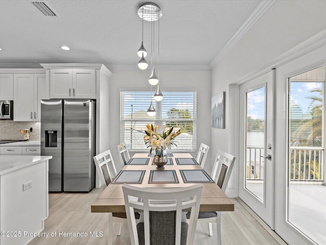 dining space with crown molding and light wood-type flooring