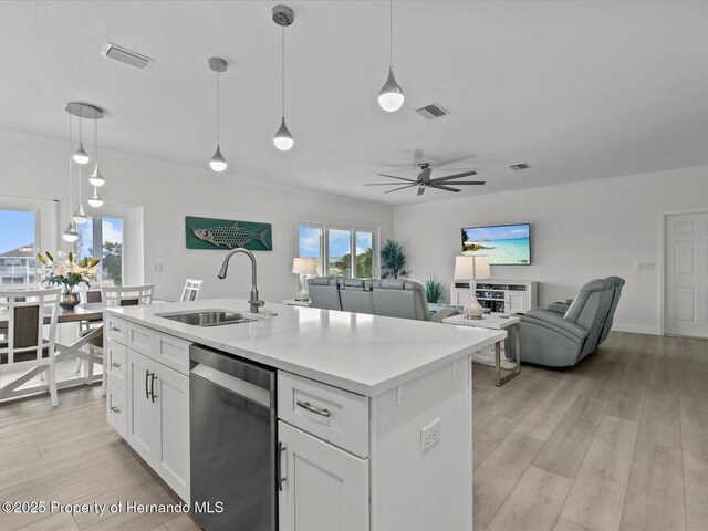 kitchen featuring pendant lighting, white cabinets, dishwasher, sink, and a center island with sink