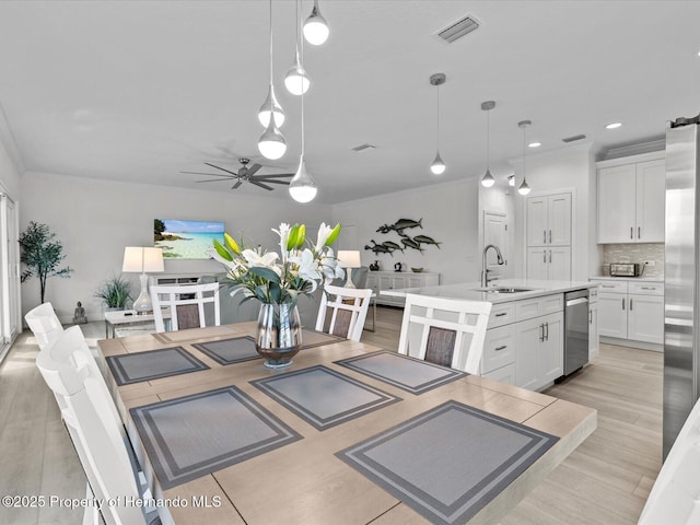 kitchen with decorative light fixtures, an island with sink, sink, and white cabinets