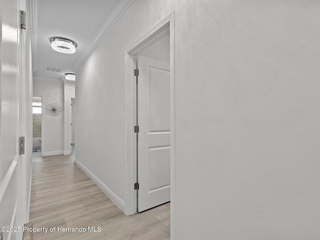 hallway with light wood-type flooring and crown molding