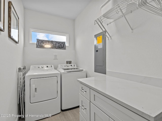 laundry area with washing machine and dryer, cabinets, electric panel, and light wood-type flooring