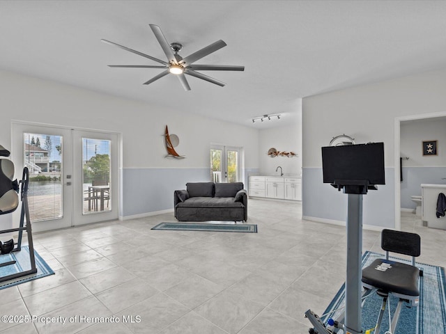 exercise area with ceiling fan, sink, light tile patterned floors, and french doors