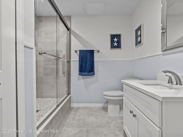 bathroom featuring a shower with shower door, vanity, tile patterned flooring, and toilet