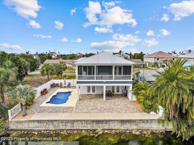 back of property with a water view, a patio, and a sunroom