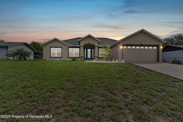 ranch-style home with a garage and a lawn