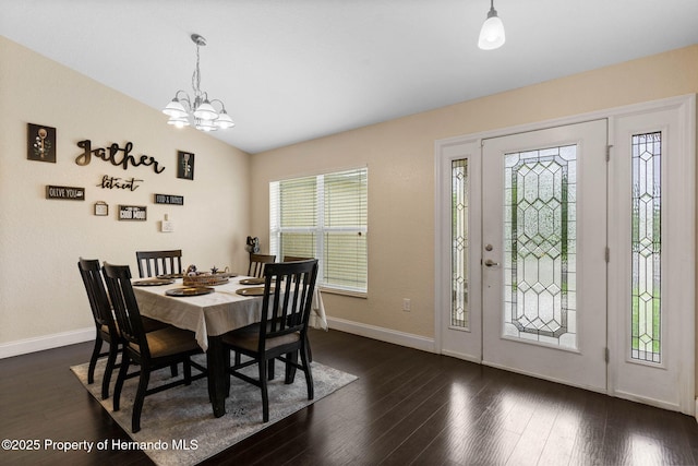 dining space featuring dark wood-type flooring, a notable chandelier, and lofted ceiling