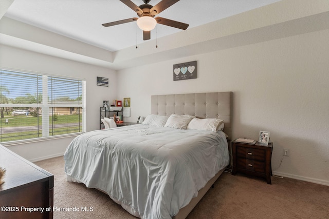 bedroom featuring light carpet, ceiling fan, and a raised ceiling