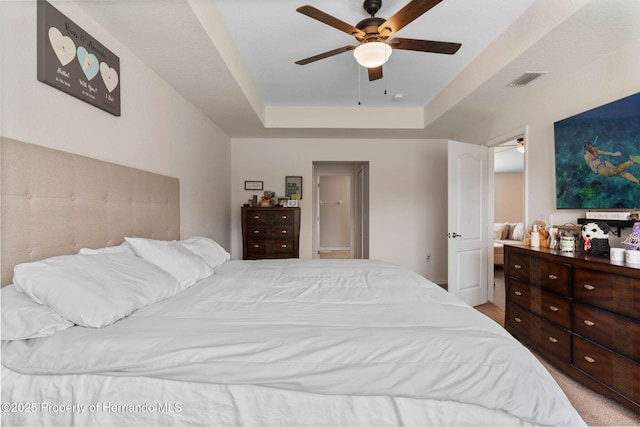 bedroom with ceiling fan and a raised ceiling