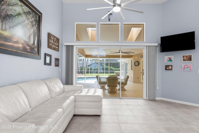 living room with ceiling fan, tile patterned flooring, and a towering ceiling