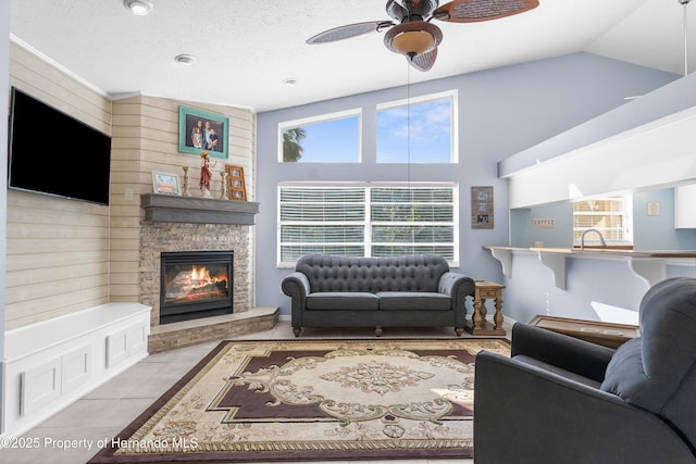 tiled living room featuring vaulted ceiling, a fireplace, sink, ceiling fan, and a textured ceiling