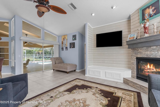 living room featuring ceiling fan, lofted ceiling, tile patterned floors, and a fireplace