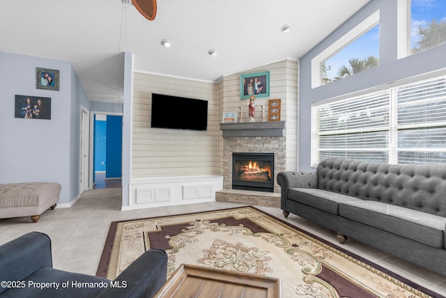 living room with light tile patterned flooring, lofted ceiling, and a stone fireplace