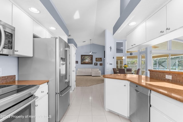 kitchen featuring lofted ceiling, white cabinets, light tile patterned floors, ceiling fan, and stainless steel appliances