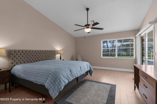 bedroom with lofted ceiling, a textured ceiling, light hardwood / wood-style flooring, and ceiling fan