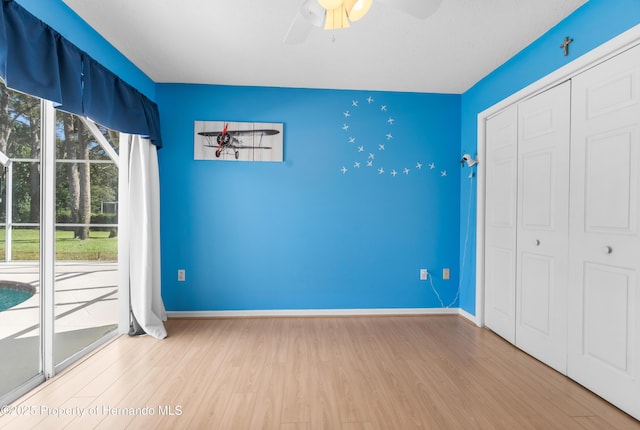 unfurnished bedroom featuring hardwood / wood-style flooring, ceiling fan, and a closet