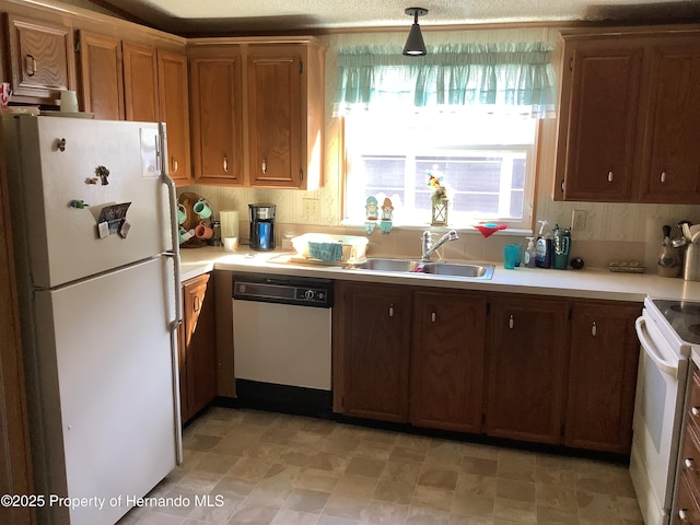 kitchen with sink, white appliances, and decorative light fixtures