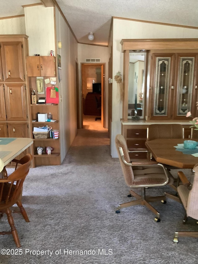 dining area with crown molding, vaulted ceiling, a textured ceiling, and carpet