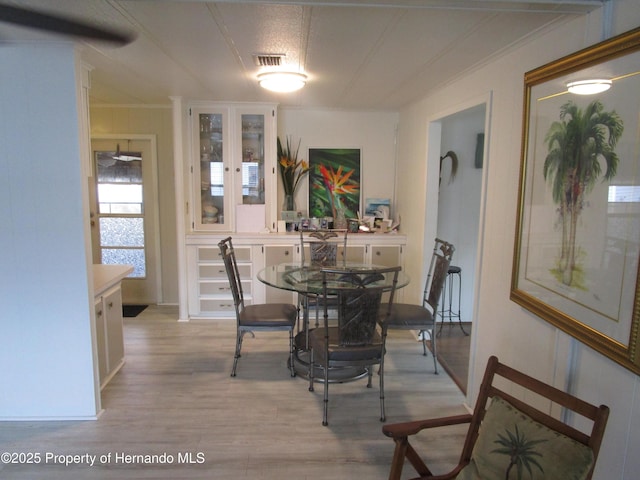 dining area with ornamental molding and light hardwood / wood-style flooring