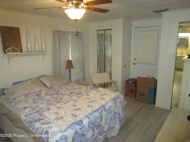 bedroom with ceiling fan, ensuite bathroom, and hardwood / wood-style floors