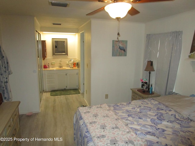 bedroom featuring ceiling fan, connected bathroom, light hardwood / wood-style flooring, and ornamental molding