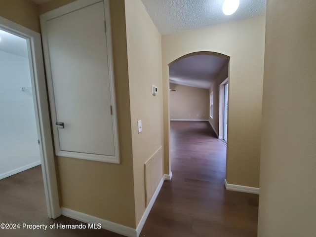 corridor with dark hardwood / wood-style floors and a textured ceiling