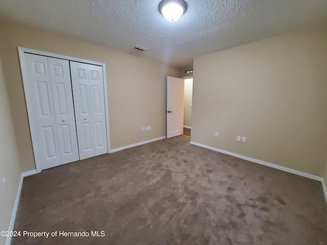 unfurnished bedroom featuring a closet, a textured ceiling, and carpet flooring