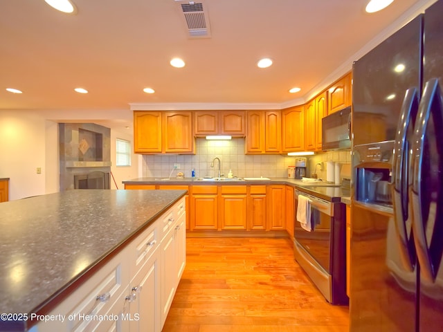 kitchen with black appliances, light hardwood / wood-style flooring, tasteful backsplash, and sink