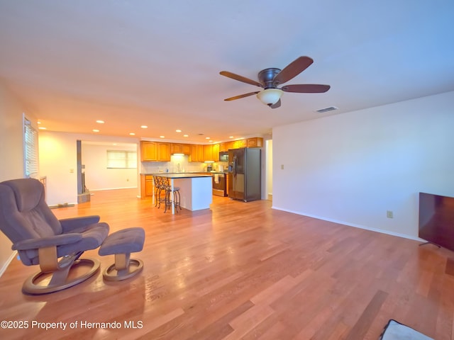 living room with ceiling fan and light hardwood / wood-style flooring