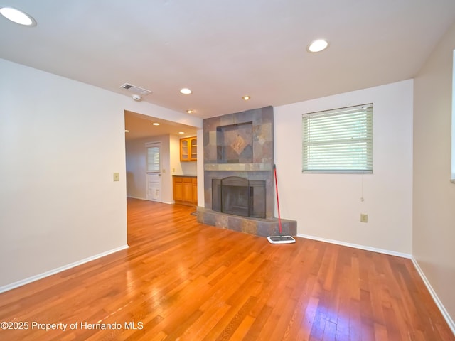 unfurnished living room featuring a tile fireplace and hardwood / wood-style floors