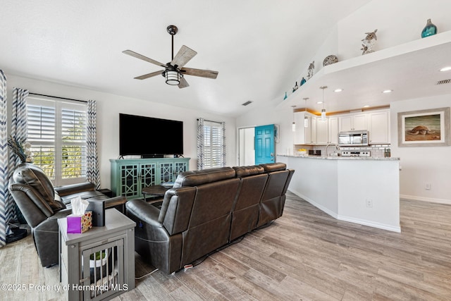 living room with ceiling fan, light hardwood / wood-style floors, and vaulted ceiling