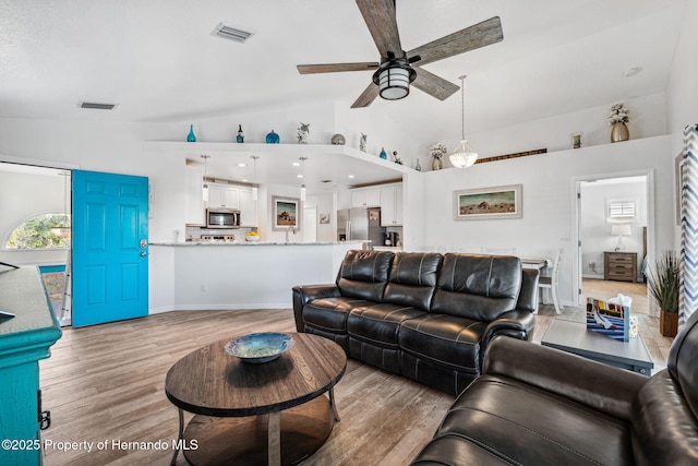 living room featuring lofted ceiling, light hardwood / wood-style floors, and ceiling fan